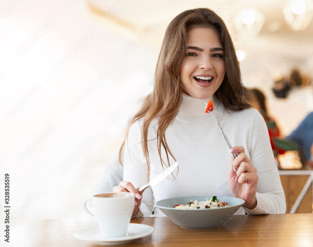 young positive beautiful woman holding fork with tomatoe while eating salad in cafe during lunch time, food and drink concept young positive beautiful woman holding fork with tomatoe while eating salad in cafe during lunch time, food and drink concept