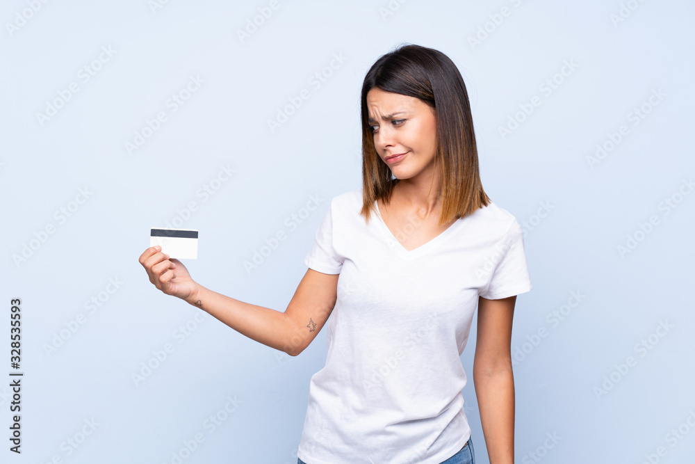 Young woman over isolated blue background holding a credit card Young woman over isolated blue background holding a credit card