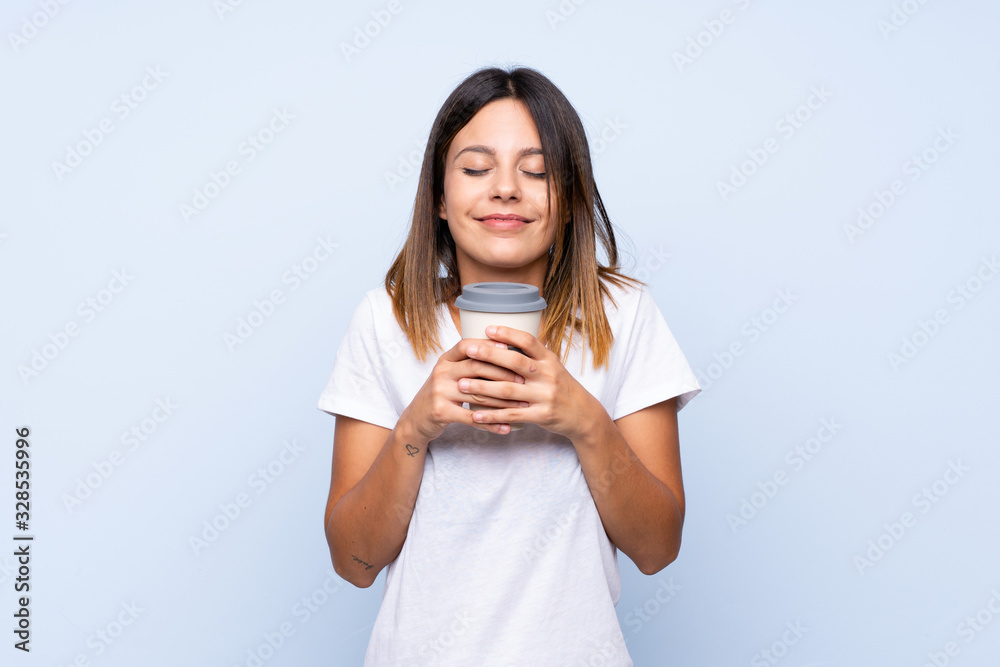 Young woman over isolated blue background holding coffee to take away Young woman over isolated blue background holding coffee to take away