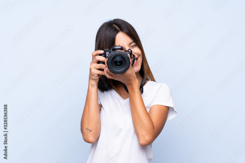 Young woman over isolated blue background with a professional camera Young woman over isolated blue background with a professional camera