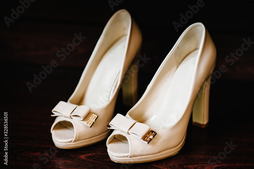 Wedding accessory bride. Stylish lacquered white shoes are isolated standing on brown background.