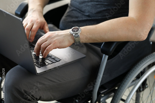 Man sitting in wheelchair working with laptop computer