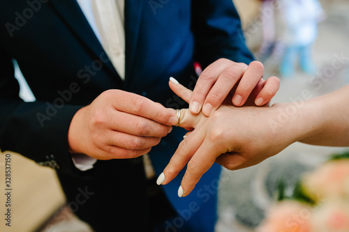 The bride's hand wears an engagement gold ring on the groom's finger. Wedding day. Hands with wedding rings. Close up.
