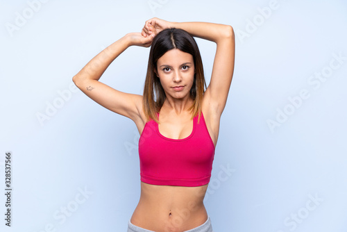 Young sport woman over isolated blue background stretching © luismolinero
