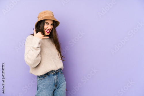 Young caucasian woman isolated on purple background showing a mobile phone call gesture with fingers.