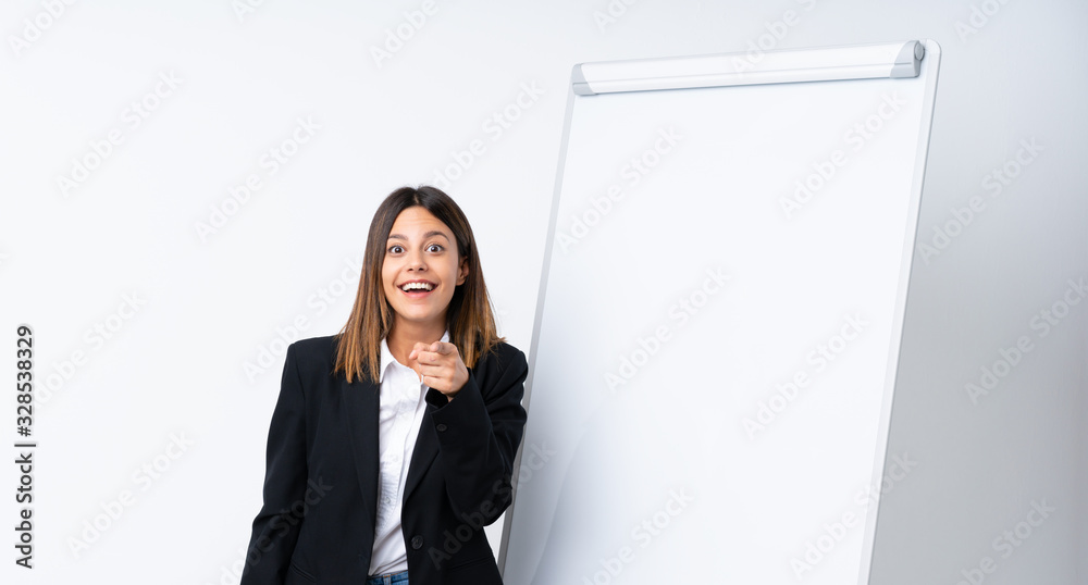 Young woman giving a presentation on white board surprised and pointing front Young woman giving a presentation on white board surprised and pointing front