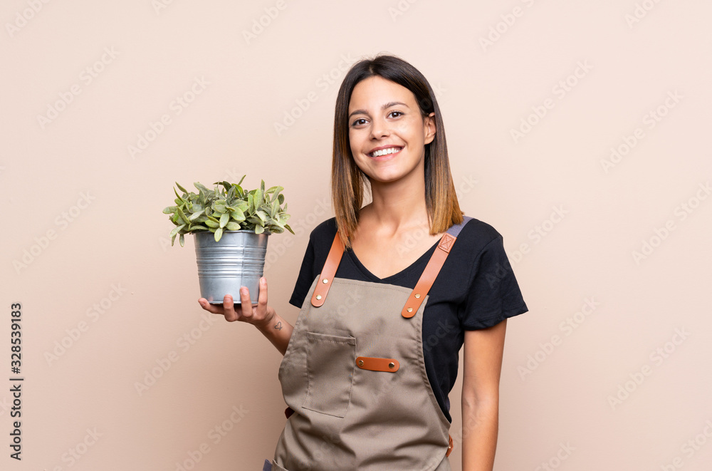 Young woman holding a plant smiling a lot Young woman holding a plant smiling a lot