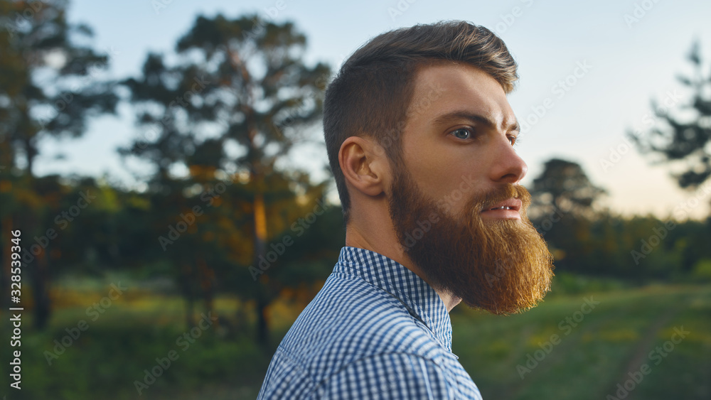 Portrait brutal bearded hipster man in forest Long red beard Blue shirt Copy free space for advertising Stock | Adobe Stock