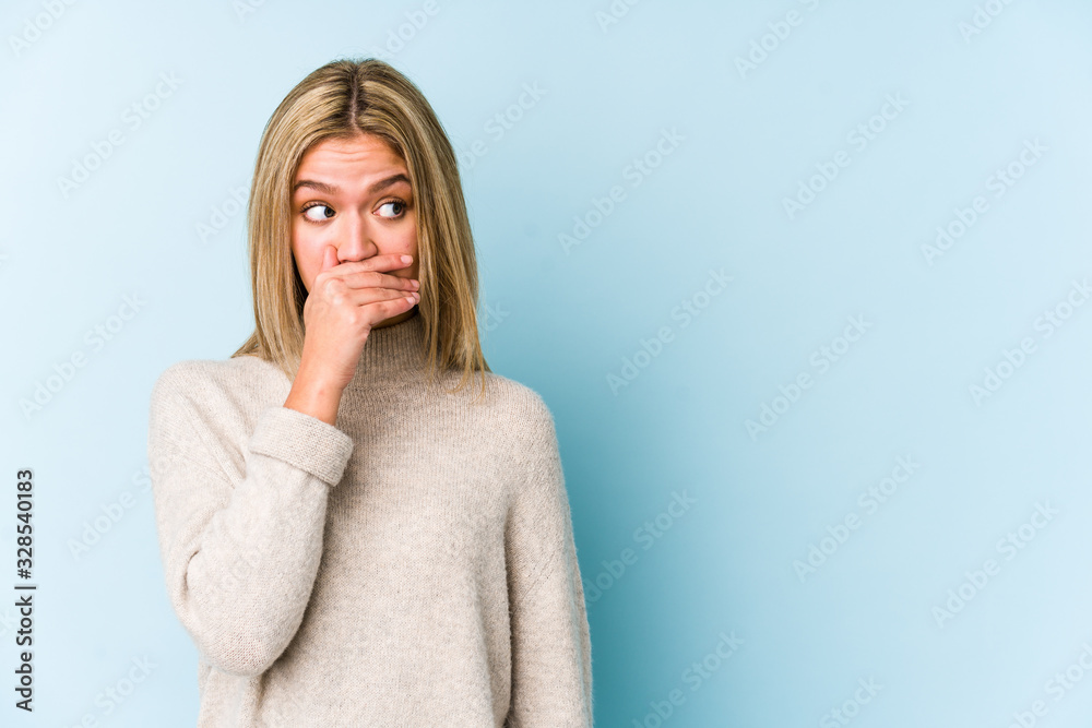 Young blonde caucasian woman isolated thoughtful looking to a copy space covering mouth with hand.