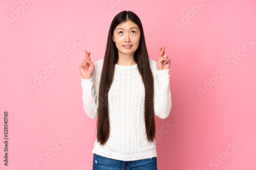 Young asian woman over isolated background with fingers crossing and wishing the best
