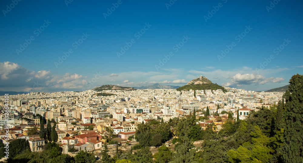 touristic and travel concept of beautiful view from top hill to city panorama of Athens - capital of Greece with many small buildings, mountains and cloudy blue sky on horizon background