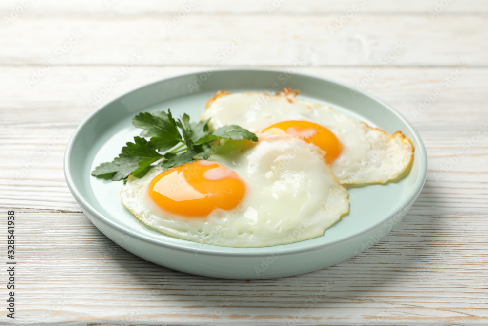 Plate with fried eggs on wooden background, close up Plate with fried eggs on wooden background, close up