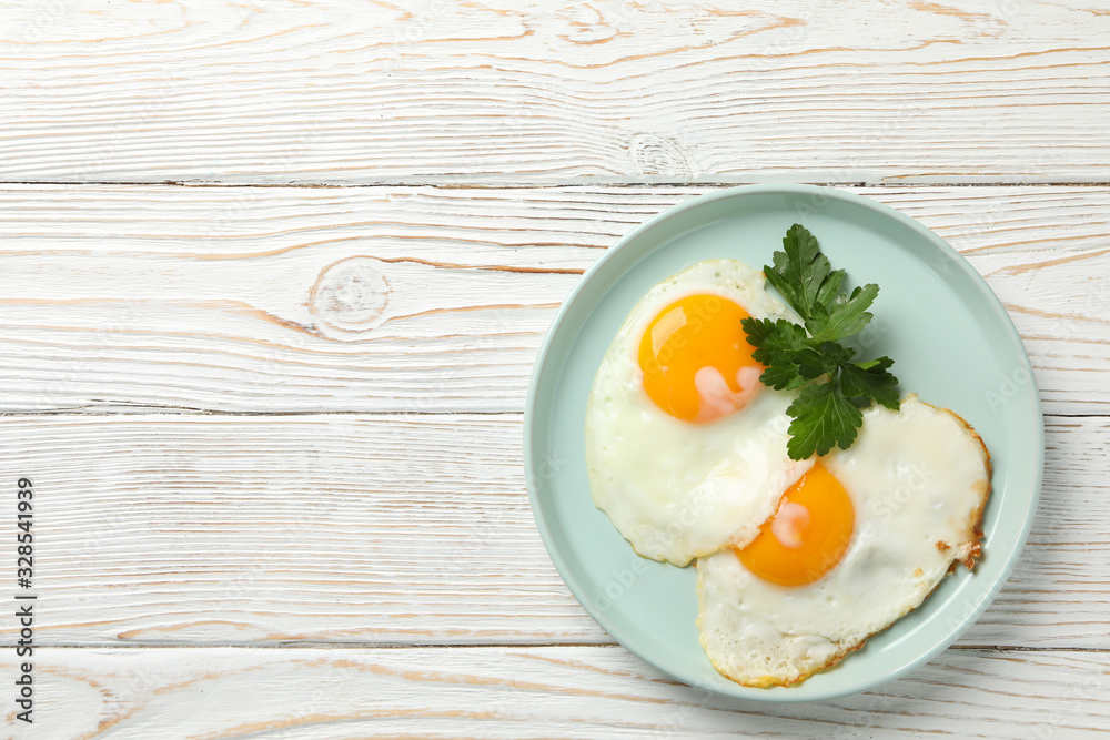 Plate with fried eggs on wooden background, top view Plate with fried eggs on wooden background, top view