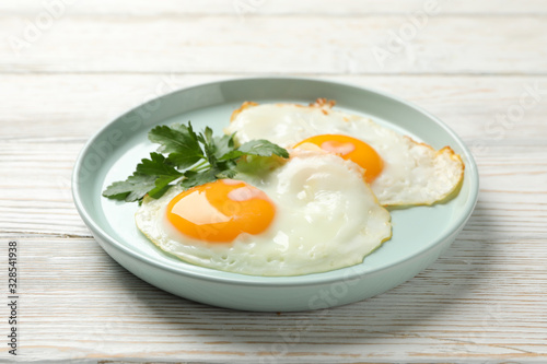 Plate with fried eggs on wooden background, close up