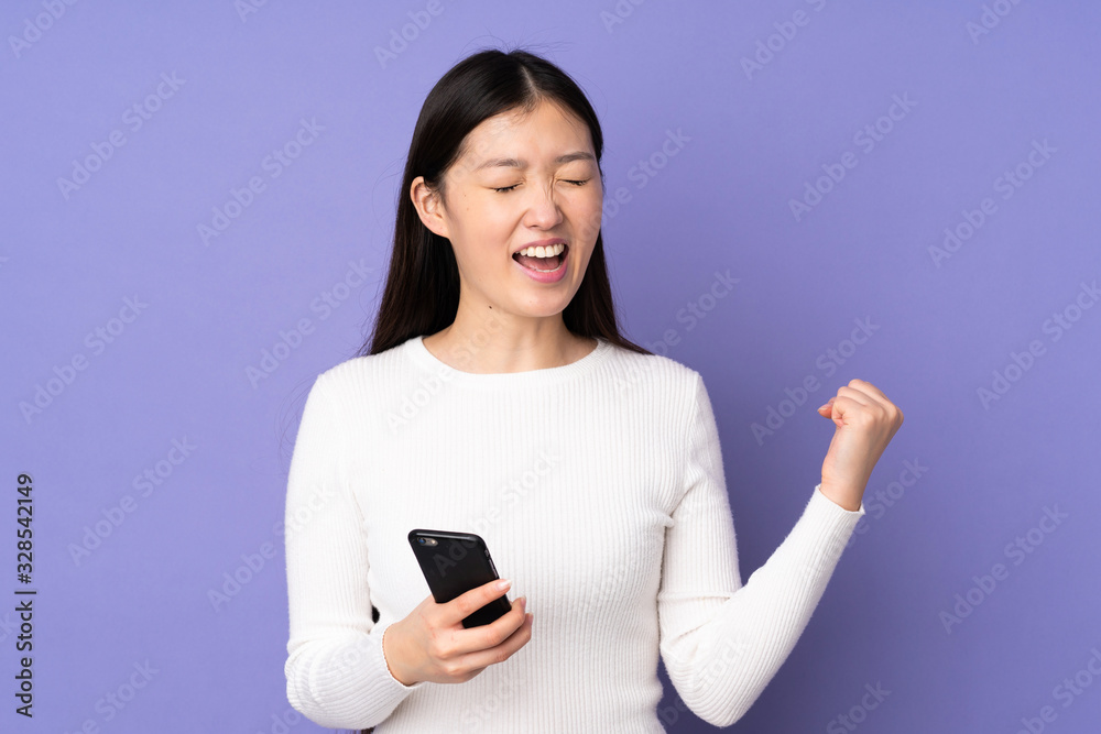 Young asian woman isolated on purple background with phone in victory position Young asian woman isolated on purple background with phone in victory position