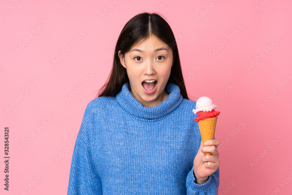 Young asian woman with a cornet ice cream isolated on pink background with surprise and shocked facial expression Young asian woman with a cornet ice cream isolated on pink background with surprise and shocked facial expression