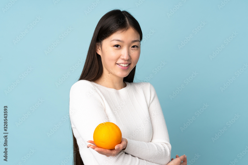 Young asian woman holding an orange over isolated blue background Young asian woman holding an orange over isolated blue background