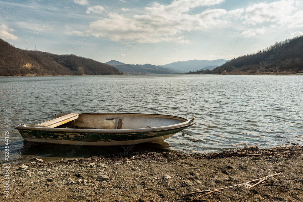 Boat on lake against mountains. Fishing boat on a still lake and mountains in background. Fishing boat Boat on lake against mountains. Fishing boat on a still lake and mountains in background. Fishing boat