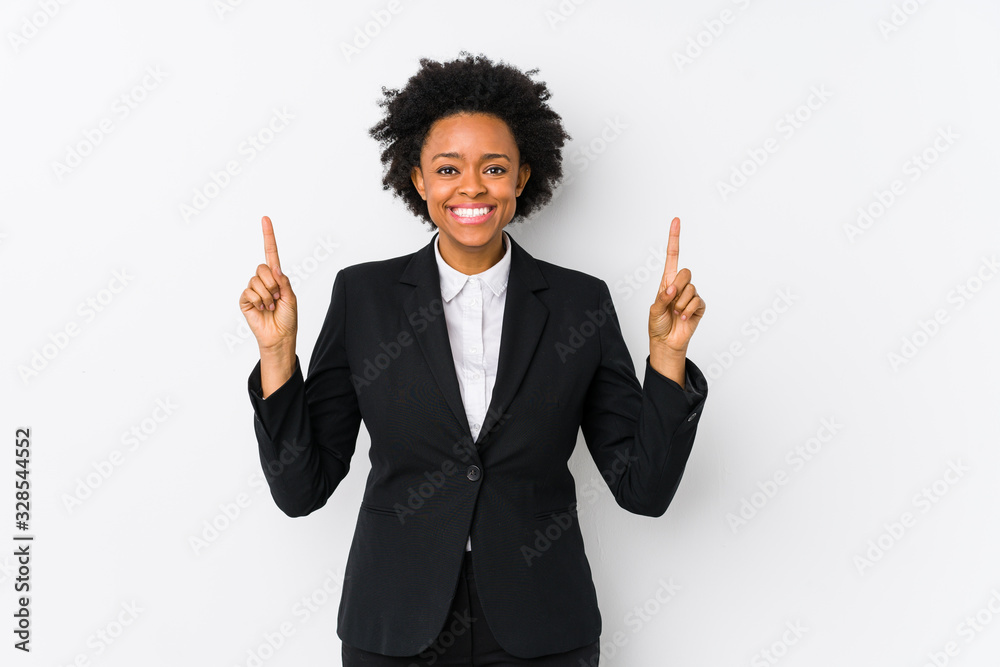 Middle aged african american business woman against a white background isolated indicates with both fore fingers up showing a blank space. Middle aged african american business woman against a white background isolated indicates with both fore fingers up showing a blank space.