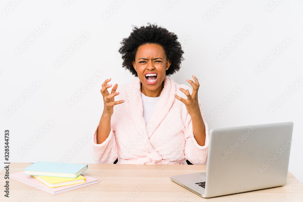Middle aged african american woman working at home isolated upset screaming with tense hands. Middle aged african american woman working at home isolated upset screaming with tense hands.