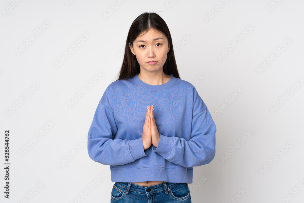 Young asian woman isolated on background keeps palm together. Person asks for something Young asian woman isolated on background keeps palm together. Person asks for something