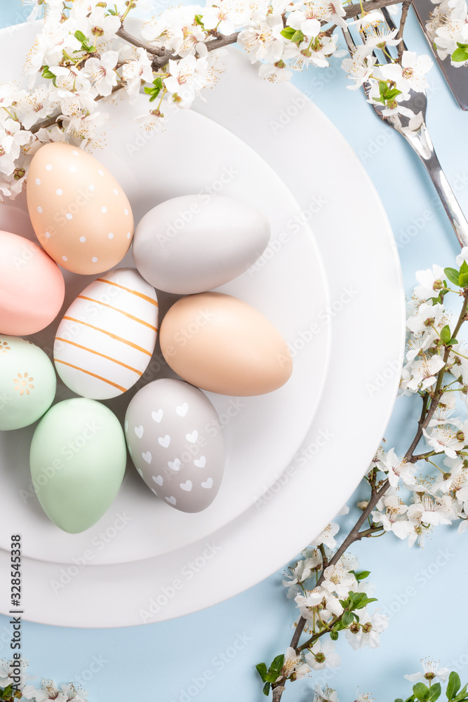 Easter table setting, holiday table home decor idea, flat lay composition with white plates, cutlery, colorful pastel painted Easter eggs, festive decor and fresh spring flowers Easter table setting, holiday table home decor idea, flat lay composition with white plates, cutlery, colorful pastel painted Easter eggs, festive decor and fresh spring flowers