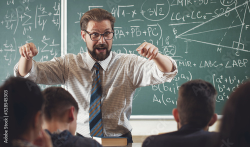 Enthusiastic math teacher explaining subject to students gesticulating with hands in schoolroom