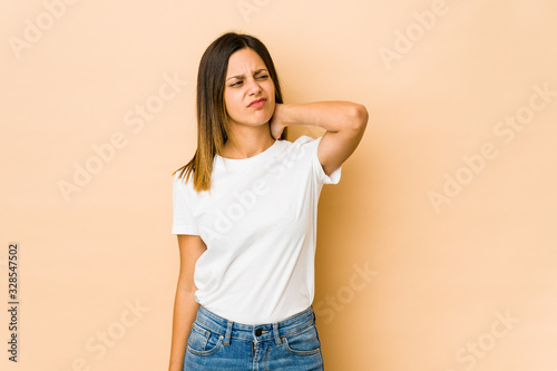 Young woman isolated on beige background suffering neck pain due to sedentary lifestyle.