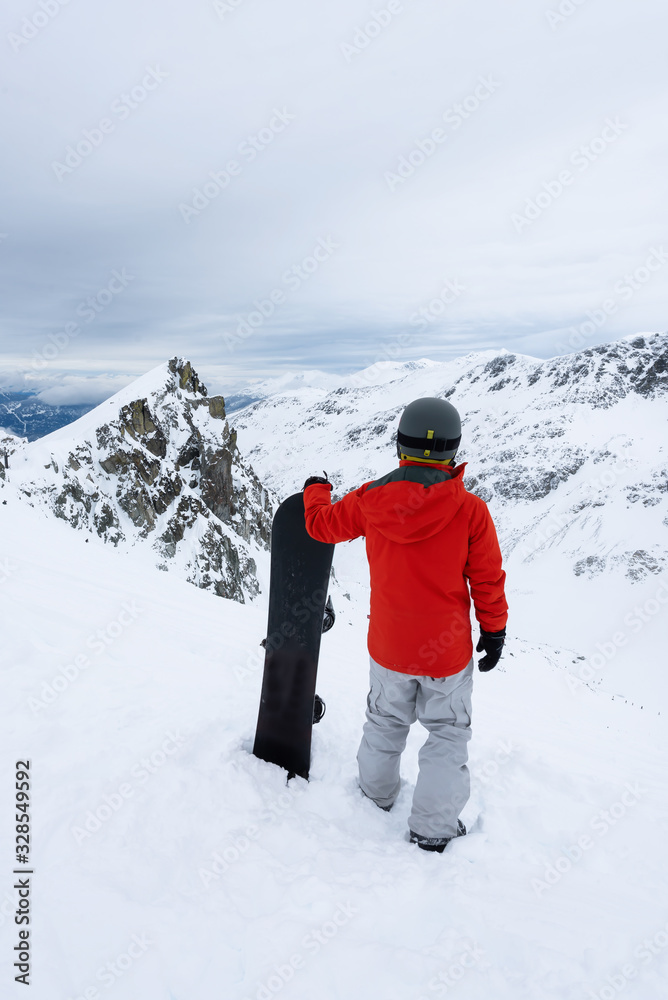Whistler, British Columbia, Canada. Adventurous Man with a snowboard in the Alpines on top of Blackcomb Mountain.