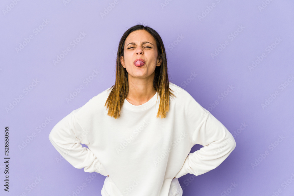 Young woman isolated on purple background funny and friendly sticking out tongue. Young woman isolated on purple background funny and friendly sticking out tongue.