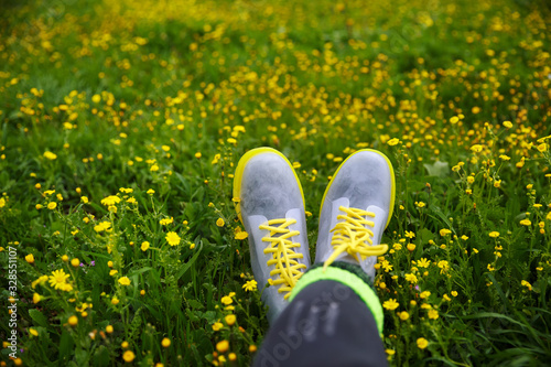 silicone shoes with yellow laces against meadows with green grass and yellow flowers