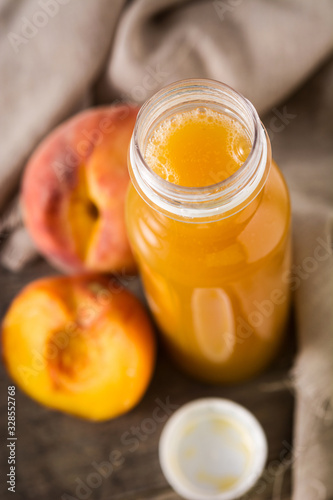 Natural peach juice in a bottle on wooden table
