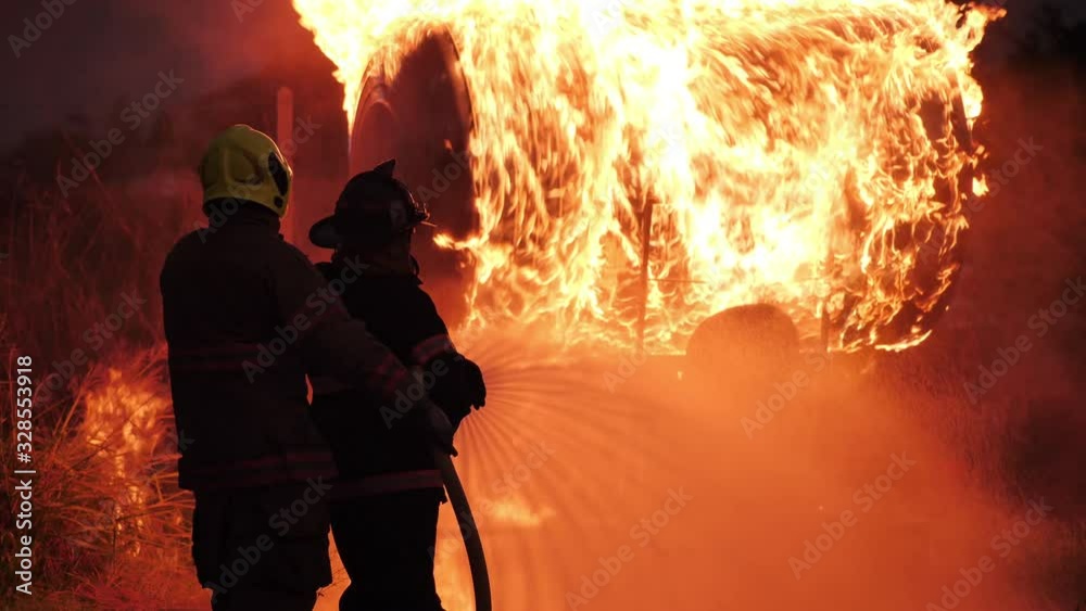 Rear view of Asian fireman wear fire protection suit. Firefighter spray water fighting at Fire station at night. Training fire drill Concept.