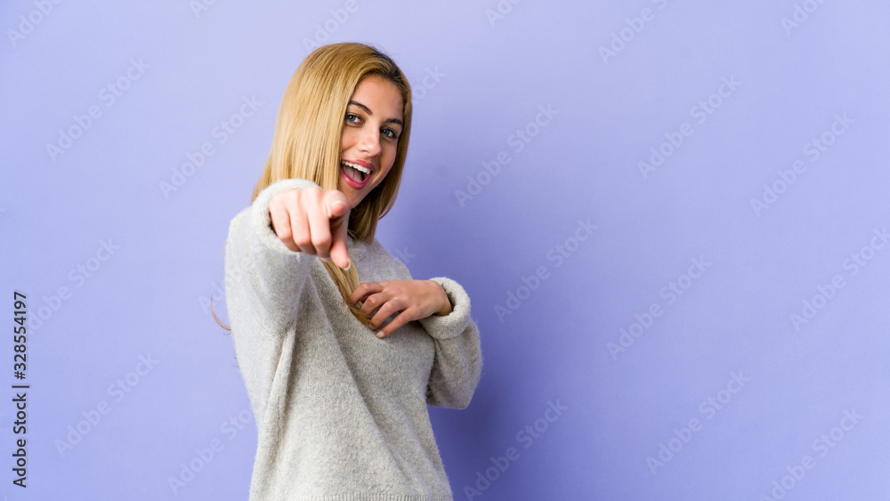 Young blonde woman isolated on purple background pointing to front with fingers. Young blonde woman isolated on purple background pointing to front with fingers.
