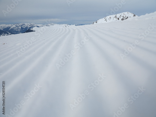 Snow velvet close up on ski slope. Prepared ski and snowboard track with trace of snow groomer on snow.
