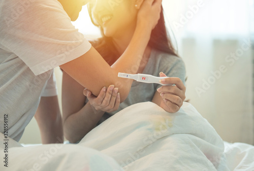 happy asian couple holding positive pregnancy test