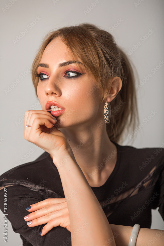 beautiful young woman with make-up in black clothes on a gray background beautiful young woman with make-up in black clothes on a gray background