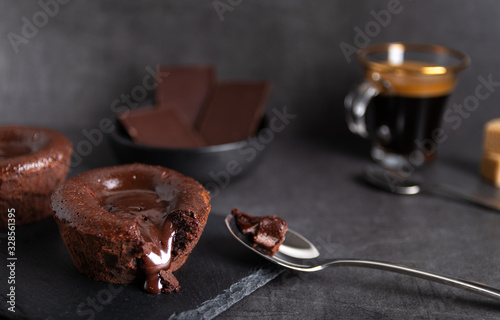 Warm chocolate lava cake on a black plate with a cup of coffee on a dark background