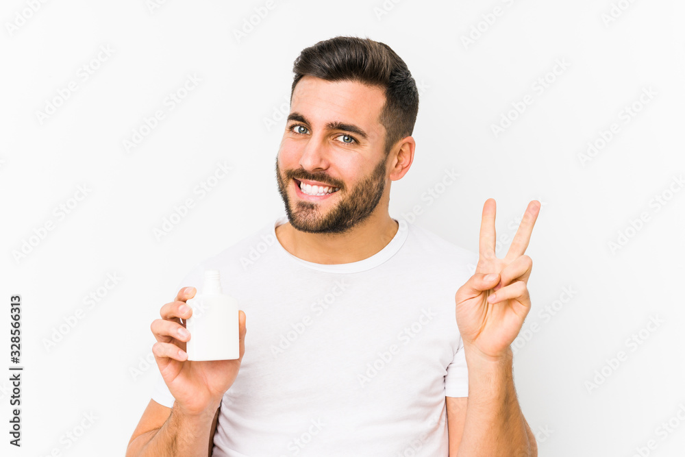Young caucasian man holding a vitamins bottle isolated showing number two with fingers. Young caucasian man holding a vitamins bottle isolated showing number two with fingers.