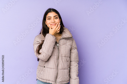 Young indian woman isolated on purple background doubting between two options.