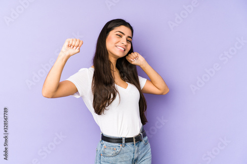 Young indian woman isolated on purple background dancing and having fun. © Asier