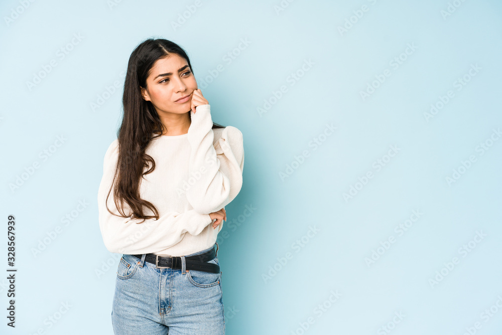 Young indian woman isolated on blue background who feels sad and pensive, looking at copy space. Young indian woman isolated on blue background who feels sad and pensive, looking at copy space.