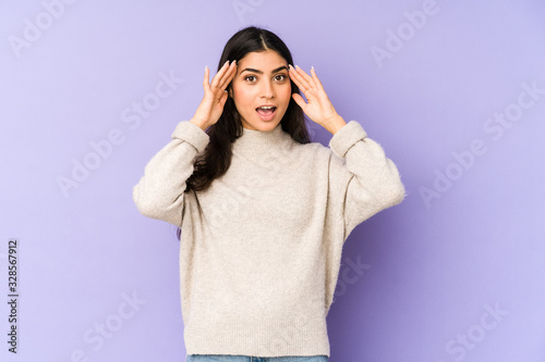 Young indian woman isolated on purple background receiving a pleasant surprise, excited and raising hands. © Asier