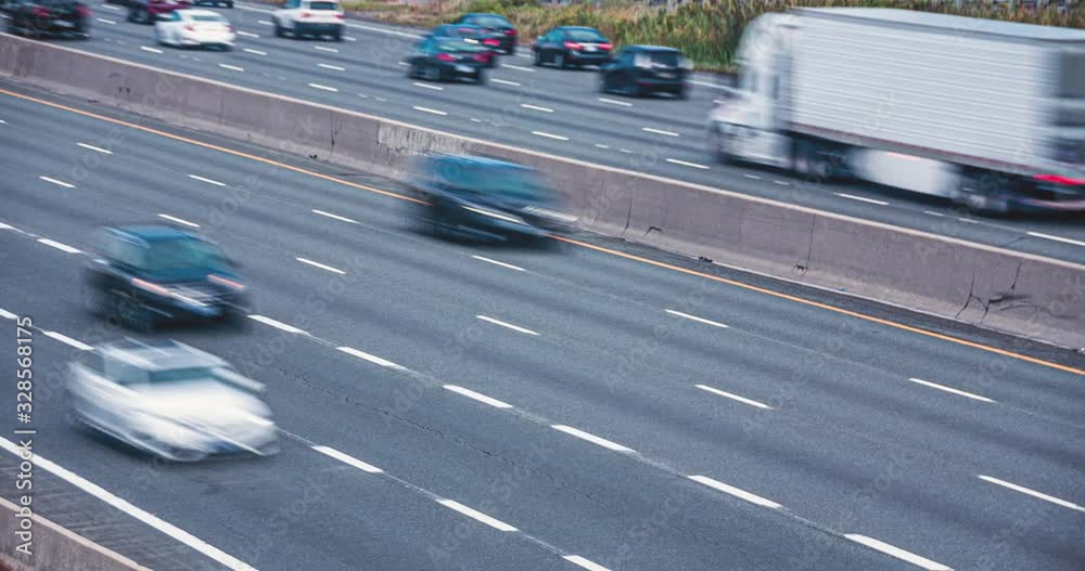 Fast moving cars and transport trucks on highway. day time traffic into city. Fast moving cars with motion blur, long exposure. 4K time lapse loop.
