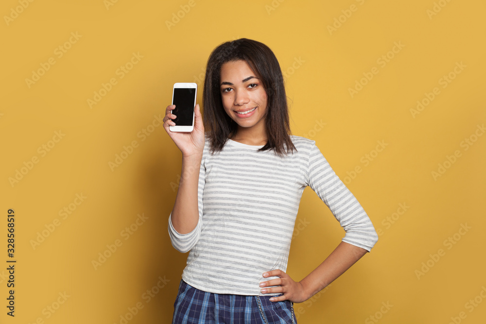 Cute black woman showing smart phone with empty display and smiling Cute black woman showing smart phone with empty display and smiling