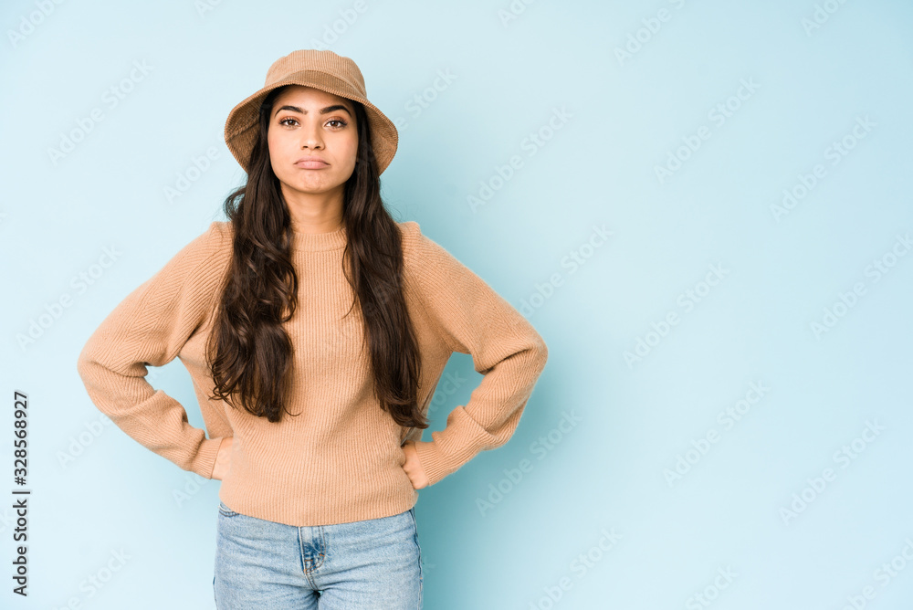 Young indian woman wearing a hat isolated on blue background sad, serious face, feeling miserable and displeased. Young indian woman wearing a hat isolated on blue background sad, serious face, feeling miserable and displeased.