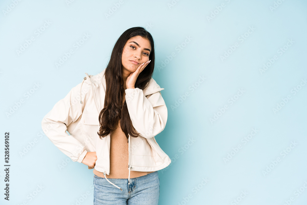 Young indian woman on blue background who is bored, fatigued and need a relax day. Young indian woman on blue background who is bored, fatigued and need a relax day.