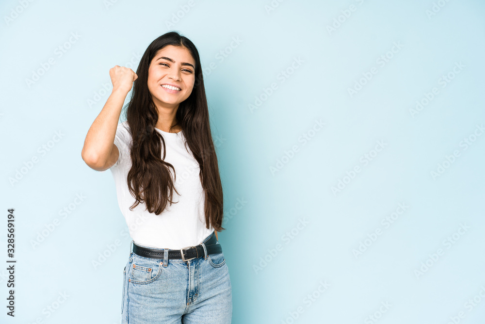 Young indian woman on blue background celebrating a victory, passion and enthusiasm, happy expression. Young indian woman on blue background celebrating a victory, passion and enthusiasm, happy expression.