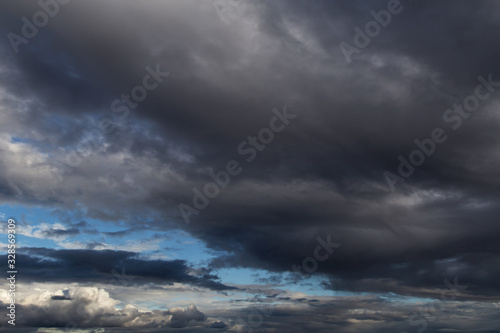 Dramatic storm dark grey cumulus clouds against blue sky background texture © Viktor Iden
