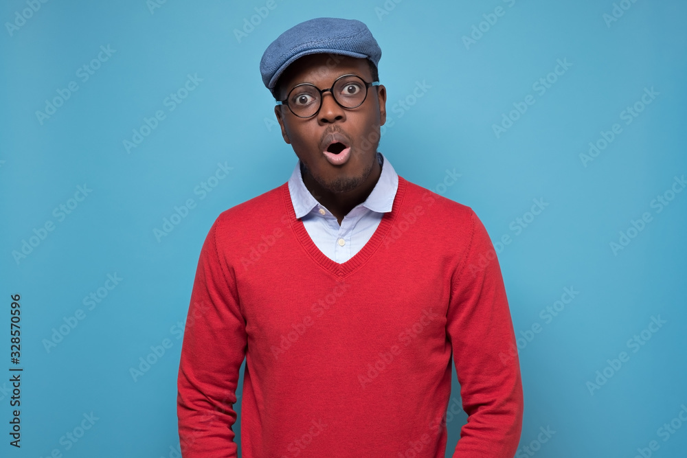 Black african american man in red sweater and blue hat looking surprised. Black african american man in red sweater and blue hat looking surprised.